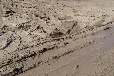 Şiddetli yağmur ve eriyen kardan sonra çamurlu yollarda lastik izleri, ıslak, çamurlu çamurlu arazide lastik izleri, off-road ortamının zorlukları.