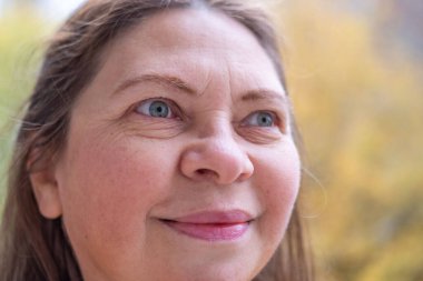 Uzun siyah saçlı bir kadın, elinde kitap kapağı ile düşüncelere dalmış bir kadın, edebi yansıma anı, doğada altın yapraklı bir kitap aşığı, kitap takdiri. 