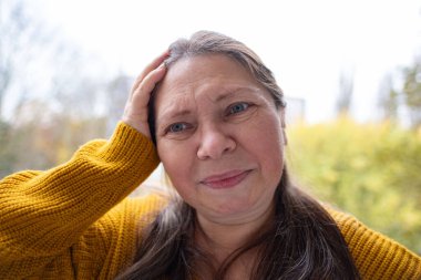 Uzun siyah saçlı bir kadın, elinde kitap kapağı ile düşüncelere dalmış bir kadın, edebi yansıma anı, doğada altın yapraklı bir kitap aşığı, kitap takdiri. 