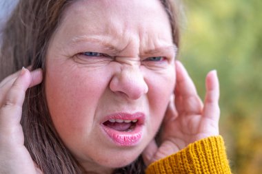 Uzun siyah saçlı bir kadın, elinde kitap kapağı ile düşüncelere dalmış bir kadın, edebi yansıma anı, doğada altın yapraklı bir kitap aşığı, kitap takdiri. 
