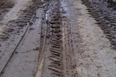 Şiddetli yağmur ve eriyen kardan sonra çamurlu yollarda lastik izleri, ıslak, çamurlu çamurlu arazide lastik izleri, off-road ortamının zorlukları.