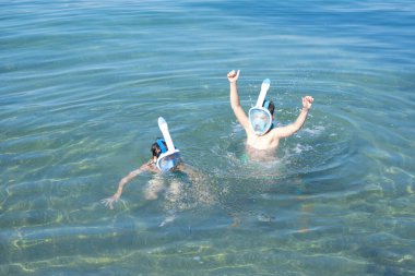 İki oğlan 10 ve 12, denizde şnorkelle yüzüyorlar. Aktif yaz tatili sırasında sualtı dünyasını maskeyle keşfeden kardeşler. Şnorkel tüplü çocukluk macerası