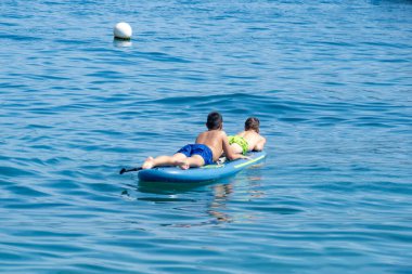 İki mutlu genç çocuk, kardeşler birlikte kürek çekiyorlar. Aktif yaz tatillerinin tadını çıkarıyorlar. Tatil, su macerası, aile denetimi, su güvenliği.