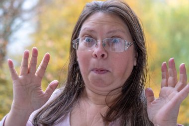 Şaşırmış, orta yaşlı, açık havada uzun saçlı bir kadın, şok olmuş bir yetişkin portresi, stres, hayat sorunları, yüz ifadesi. Şok, şaşkınlık ve beklenmedik duygular konsepti