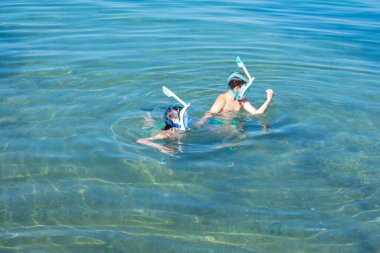 İki küçük çocuk, kardeşler denizde şnorkelle yüzüyor güneşli bir yaz gününde okyanus dalgaları, aile aktiviteleri, yaz maceraları çocuklarda merak ve çevreye olan sevgiyi arttırıyor.