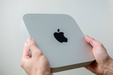 Mac Mini M1 bilgisayarı erkeklerin elinde, Apple logosu, teknolojik taşınabilirlik, uzaktan kumandalı ev ortamında çalışıyor, uzaktan kumandalı iş, vites küçülten yaşam tarzı, Frankfurt - 4 Şubat 2025