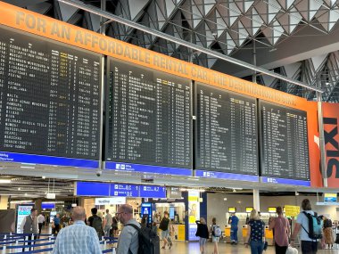 Uçak kalkış bilgi panosu, havaalanı terminali yolcuları kontrol ediyor, büyük kalkış panosu varış noktalarını gösteriyor. Havaalanı seyahat salonu, Frankfurt - 6 Ağustos 2024