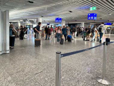 Uçak kalkış bilgi panosu, havaalanı terminali yolcuları kontrol ediyor, büyük kalkış panosu varış noktalarını gösteriyor. Havaalanı seyahat salonu, Frankfurt - 6 Ağustos 2024