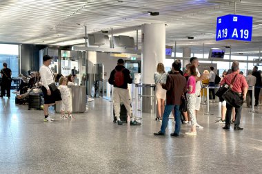 Uçak kalkış bilgi panosu, havaalanı terminali yolcuları kontrol ediyor, büyük kalkış panosu varış noktalarını gösteriyor. Havaalanı seyahat salonu, Frankfurt - 6 Ağustos 2024