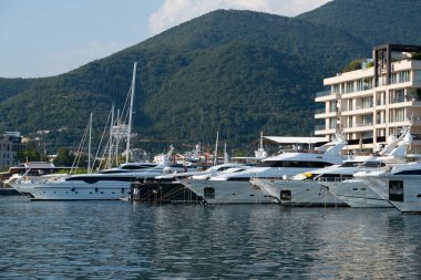 Karadağ limanı, çağdaş binalar, zarif konutlar, Tivat tatil beldesi ve yüksek yeşil dağlar tarafından desteklenen kıyı Modern Upscale marinasında sıra sıra dizilmiş lüks yatlar.