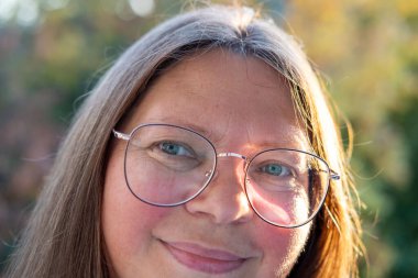 Rahatlamış tombul bir kadın, mutluluğu nazikçe kucaklıyor, doğada duruyor, sıcak kalpli bir kadın, sevgisini ve takdirini ifade ediyor, olgun bir kadın yüzü, kendine bakım, rahatlama ve ahenk kavramını kavrıyor.