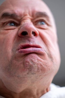 Kızgın yaşlı adam, çatık kaşlı, yoğun bakışlı ve büzüşmüş dudaklı. Ciddi kıdemli adam agresif ve üzgün görünüyor, güçlü duygularını ifade ediyor, saldırganlığı, gerilimi ve yüzleşmeyi kavrıyor.
