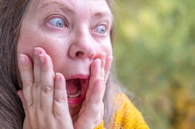 Yakın plan kadın yüzü şaşkınlık ve korku gösteriyor, korkmuş ve şaşırmış orta yaşlı kadın, korkmuş ve ürkek ifade, şok ve korku ileten yoğun tepki. Etkileyici bir portre şoku