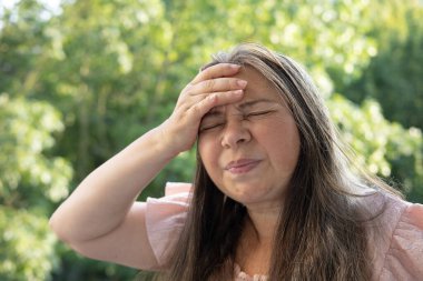 50-55 yaşlarındaki olgun bir kadın şiddetli baş ağrısı, menopoz sırasında sıcak basması, hafıza ve konsantrasyonunun azalması, gergin hissetmesi, yorgun ve bitkin hissetmesi,