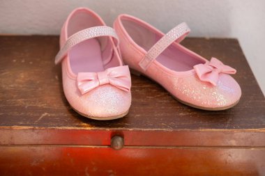 Yaylı parlak pembe ayakkabılar, bireyselliği, özgüveni ve yeni becerilerde, çocuk modasında ustalaşma kararlılığını, bağımsızlığı simgeler.