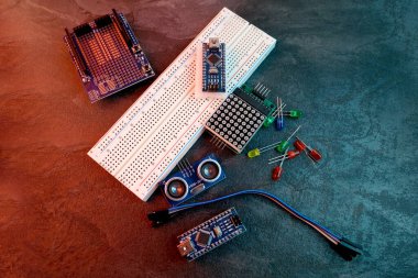Elektronik bileşenler, akü kabloları ve ekmek tahtasıyla dolu kutuda, DIY projelerini, devre binasını, elektronik prototipleri, hobi teknolojisini, elektrik mühendisliğini sembolize ediyor.
