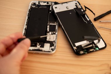 Teknisyen akıllı telefonu hassas aletlerle tamir ediyor. Cep telefonu donanım bileşenlerini, teknik desteği, DIY tamirhanesini, servis donanımını, telefon donanımını tamir eden elleri kapatın