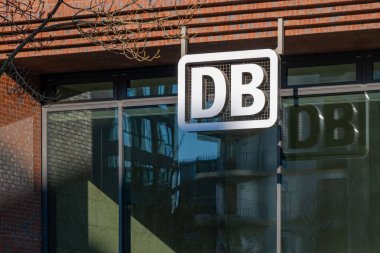 Mavi gökyüzüne karşı belirgin ikonik DB logosu olan modern bina, Deutsche Bahn şirketinin taşımacılık ve cam cephe bağlantısına karşı bağlantı, Frankfurt - 19 Ocak 2025