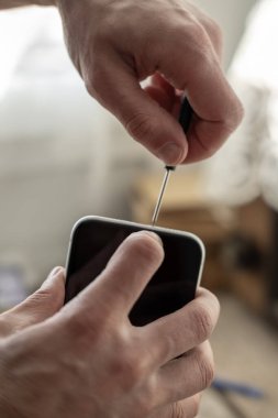 Teknisyen akıllı telefonu hassas aletlerle tamir ediyor. Cep telefonu donanım bileşenlerini, teknik desteği, DIY tamirhanesini, servis donanımını, telefon donanımını tamir eden elleri kapatın