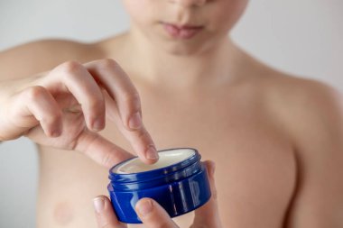 Ergenlik çağında yüzlerine sivilce kremi süren, hormonal sivilcelerle uğraşan, sağlıklı kişisel bakım rutinleri geliştiren, tipik ergenlik değişimleri ve duygusal zorluklarla yüzleşen bir çocuk.