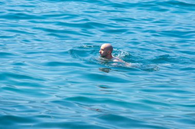 Denizde, okyanusta genç bir yüzücü, su sporlarıyla uğraşan bir adam, tehlikeli akıntılarla mücadele eden, görülmemiş tehlikeler hakkında uyaran, aktif yaşam tarzı