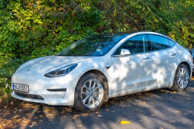 beyaz Tesla Model 3 şehir merkezine park edilmiş, ev arabası Avrupa şehir sokağına park edilmiş, otomotiv endüstrisi, geleceğin arabası, Frankfurt - 11 Ekim 2024