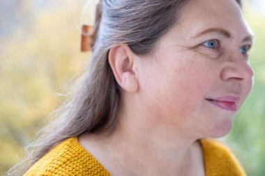 Rahatlamış tombul bir kadın, mutluluğu nazikçe kucaklıyor, doğada duruyor, sıcak kalpli bir kadın, sevgisini ve takdirini ifade ediyor, olgun bir kadın yüzü, kendine bakım, rahatlama ve ahenk kavramını kavrıyor.