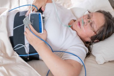 Karnına taşınabilir uyku cihazı takan kadın, uykulu kadın hasta ve karın bölgesinde sağlık izleme cihazı ve sürekli takip için parmak ucu nabız oksimetresi, horlama problemleri.