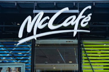 Modern cam cephe üzerine McKafe logosu, kahve kültürü markalaşması, kentsel kafe girişi, çağdaş bina dışı, stilize tabela, şehir hayatı, iş cephesi, yansımalar, Berlin - 25 Nisan 2024 