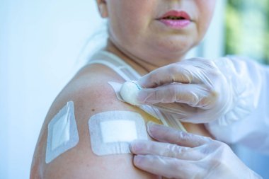 Doktor, cerrahi yarayı, kadın hastayı, omuz yaralanmasını, steril aletleri, iyileşme sürecini, klinik hijyeni, ameliyat sonrası bakımı, tıbbi profesyonel temizlik prosedürünü, 