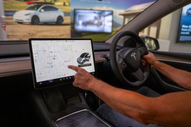 Tesla Model Y sürücüsü dikkatleri merkezi ekrana, modern sol sürücü iç dizaynına, yüksek teknoloji arayüzüne, kontrol paneline, son model otomotiv ortamına, Londra - 17 Eylül 2024
