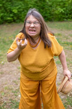 Saldırgan orta yaşlı kadın dışarıda negatif duygular sergiliyor. Çevresi yeşillik ve dingin çevreyle çevrili. Öfke ve gerilimle reaksiyon gösteriyor.