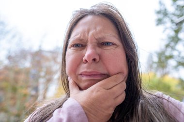 Yakın plan olgun kadın 50 yaşında, insan boynu, yerçekimsel ptosis, çift sarkık çene, Yaşlanma ve Yüz Görünümü, yaşla ilgili deri değişiklikleri, kozmetik yaşlanmayı önleme prosedürleri, cilt sıkılaştırma