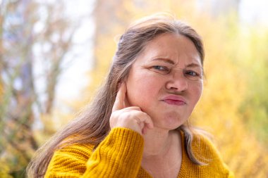 Kulaklarını acılı ifadeyle kaplayan kadın, gürültüden rahatsız olan duygusal portre, çevresel gürültü etkisi portresi, yüksek seslere kendiliğinden tepki, gerçek yüz ifadesi.