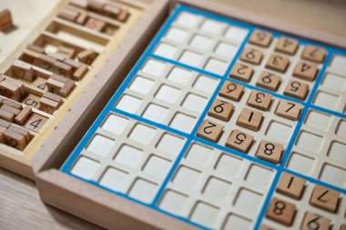 Sayıyı Sudoku yapbozuna dikkatlice yerleştiren eller, meydan okuyucu bulmacaları çözmeye, zihinsel uyarımlara ve klasik oyunlardan keyif almaya kendini kaptırmış yaşlı kişi,