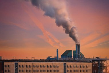 Bacadan çıkan buharlı dramatik manzara fabrikası, gün batımına doğru yükseliyor, gücü ve endüstriyi yakalıyor, sanayileşmenin çevresel etkisi, modern dünyanın sürdürülebilir uygulamaları, 
