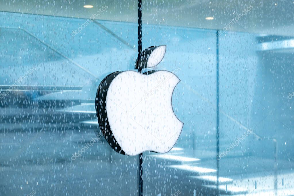 White Apple store logo on transparent glass storefront, iPhone, iMac company branding, modern brand business, tech branding, urban environment, Milan, Italy - May 21, 2025