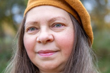 Pozitif orta yaşlı kadın, hardal kıyafetli, temiz havanın tadını çıkarıyor, sonbaharda orman, sonbahar havası, mutluluk doğa yürüyüşü, sonbaharın tadını çıkarıyor, gülümsüyor, neşeli bir ifade, açık havada, açık havada olgun bir portre