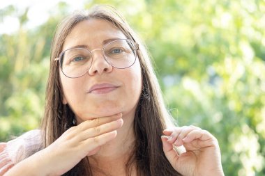 Kapalı yüz, olgun kadın 55 yaşında, insan boynu, çift sarkık çene, yaşlanma ve yüz görünümü, yaşla ilgili deri değişiklikleri, kozmetik yaşlanmayı önleme prosedürleri, cilt sıkılaştırma