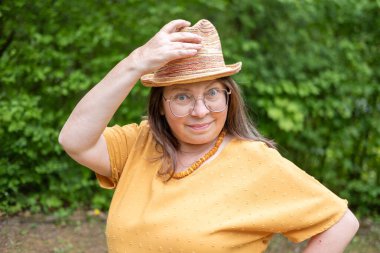 Şık, yaşlı, mutlu, sarı kıyafetli, şapkalı, hardallı, açık havada gülümseyen olgun bir kadın. Yaz ya da bahar, doğal görünüş, günlük yaşam tarzı, gerçek kadınlar için moda.