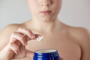 Ergenlik çağında yüzlerine sivilce kremi süren, hormonal sivilcelerle uğraşan, sağlıklı kişisel bakım rutinleri geliştiren, tipik ergenlik değişimleri ve duygusal zorluklarla yüzleşen bir çocuk.