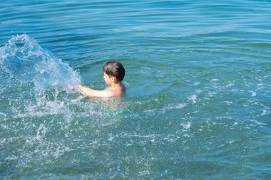 Genç çocuk açık denizde, güneşli bir yaz gününde okyanusta, su aktivitelerinde, boğulmayı önler, su maceraları çocuklarda merak ve çevreye olan sevgiyi artırır.