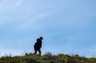 Mutlu genç çocuk volkanik uçurum kenarında duruyor, Madeira adasında yürüyüş yapıyor, sonsuz mavi Atlantik okyanusuna bakıyor, okyanus kıyısında dinlendirici yürüyüşün tadını çıkarıyor.