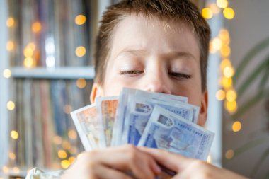çocuk 10 yaşında, ilkokul öğrencisi, elinde İngiliz sterlin notları tutan çocuk, finansal özgürlük, gerçek insanlar, kağıt para, yetişkin taklidi