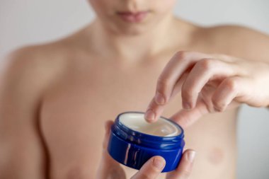 Ergenlik çağında yüzlerine sivilce kremi süren, hormonal sivilcelerle uğraşan, sağlıklı kişisel bakım rutinleri geliştiren, tipik ergenlik değişimleri ve duygusal zorluklarla yüzleşen bir çocuk.