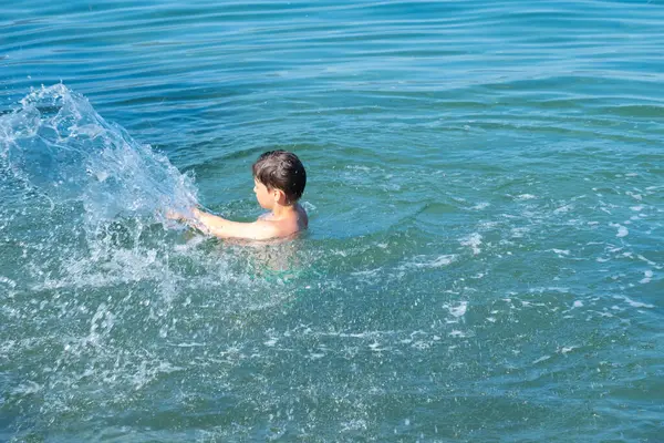 Genç çocuk açık denizde, güneşli bir yaz gününde okyanusta, su aktivitelerinde, boğulmayı önler, su maceraları çocuklarda merak ve çevreye olan sevgiyi artırır.