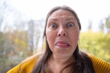 Yakın plan orta yaşlı kadın şok olmuş ve şaşkın bir ifadeyle, geniş gözler ve açık bir ağızla derin bir şaşkınlık, duygusal dramatik bir portre, şaşkınlık ve huşu sergiliyor. 