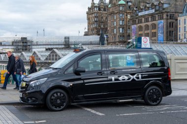 Siyah klasik İngiliz taksisi Edinburgh caddesinde, geleneksel taksi, tarihi mimari, miras atmosferi, ulaşım havası, sokak fotoğrafçılığı atmosferi, İngiliz havası, Edinburgh - 15 Nisan 2025