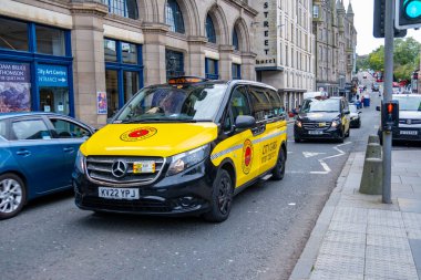 Siyah sarı klasik İngiliz taksisi Edinburgh caddesinde, geleneksel taksi, tarihi mimari, ulaşım seyahat havası, sokak fotoğrafçılığı, şehir seyahati atmosferi, İngiltere atmosferi, Edinburgh - 15 Nisan 2025