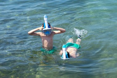Denizde yüzen iki çocuk, mavi şişme salda sürükleniyorlar, açık denizde kaza yapıyorlar, şişme bot denizde daha da uzağa sürükleniyor, güçlü akıntıyla, su güvenliğiyle. 